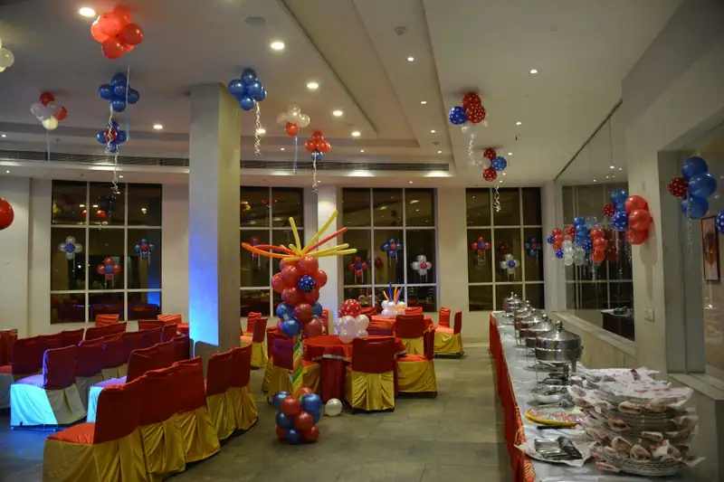 A banquet hall with a long buffet counter of chafing dishes down one side and seating opposite.